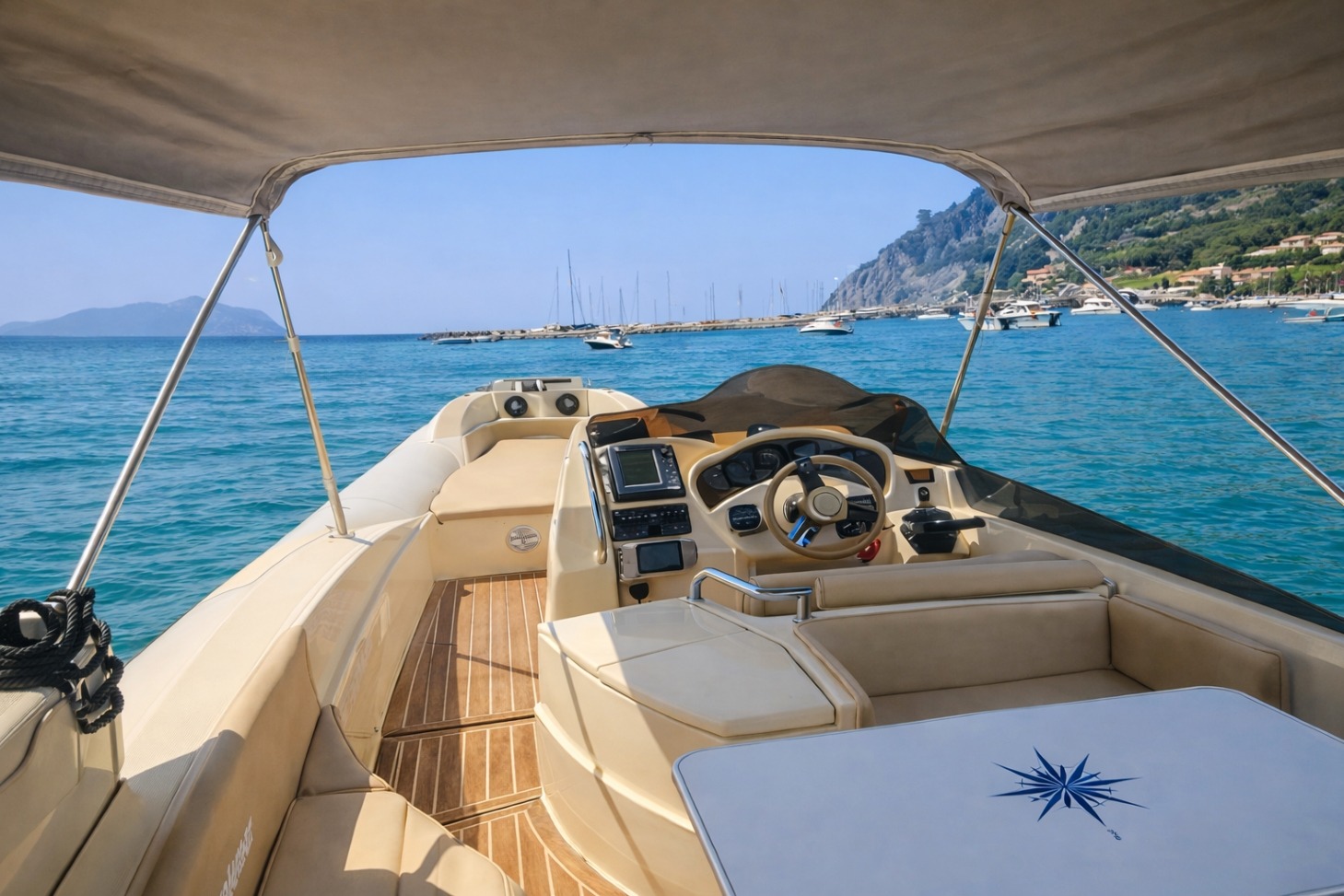 Interno di un gommone Solemar Offshore da 10 metri, con sedute beige, tavolino con rosa dei venti e timoneria vista mare. Sullo sfondo, acque turchesi e barche ancorate vicino alla costa di Ponza sotto un cielo limpido.